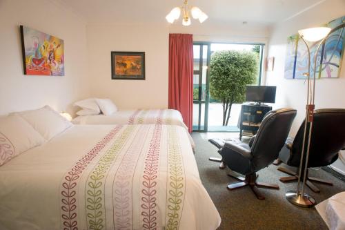 a hotel room with a bed and a desk and chairs at Greenmeadows on Gloucester in Napier
