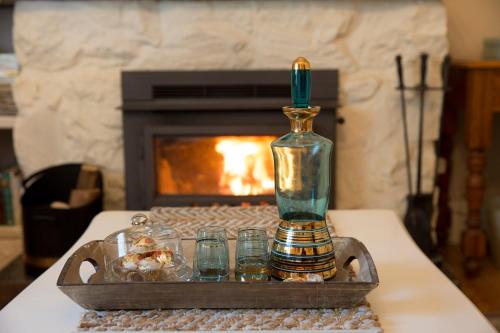 a bottle and glasses on a table with a fireplace at Azalea Cedar-Rose Barossa Valley Villa in Lyndoch