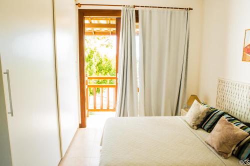 a bedroom with a bed and a sliding glass door at Apartamento Terraco Buganvilias - Reserva Imbassai in Imbassai