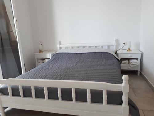 a white bed in a bedroom with two night stands at Sunset in Iraklia