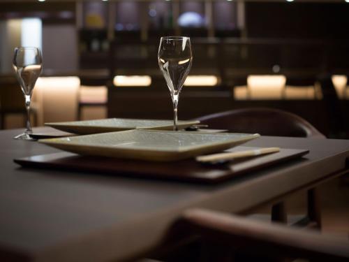 a table with a plate and two wine glasses on it at Saka Hotel Kyoto in Kyoto