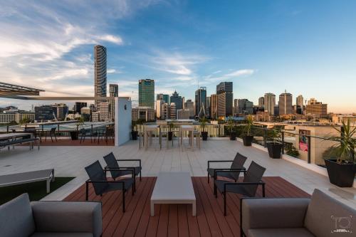 a rooftop patio with tables and chairs and a city skyline at Fleet Lane Apartments in Brisbane