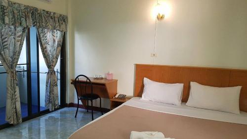 a bedroom with a bed and a desk and a window at LP Mansion in Sakon Nakhon