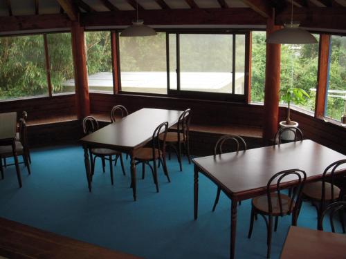 un comedor con mesas, sillas y ventanas en Guest House Ishitatu, en Shimoda