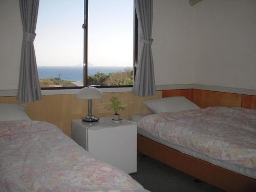 a hotel room with two beds and a window at Guest House Ishitatu in Shimoda