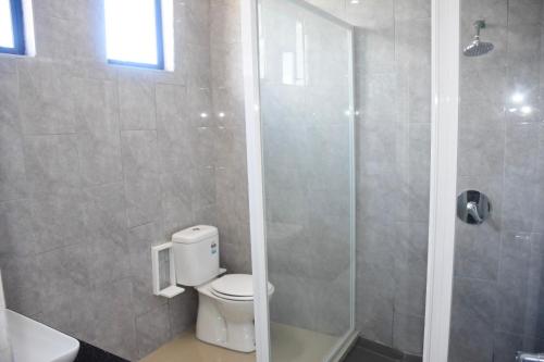 a bathroom with a toilet and a glass shower at Best View Apartments in Nadi
