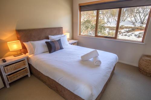 a bedroom with a large white bed with a window at Sambuca in Mount Hotham