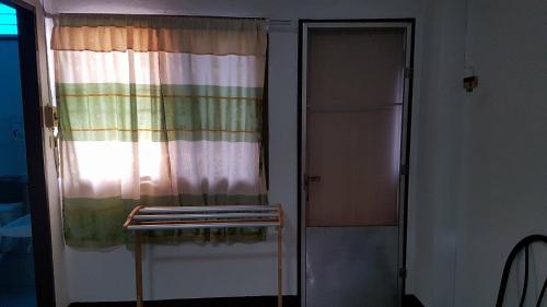 a room with a curtain and a window with a shelf at LP Apartment in Sakon Nakhon