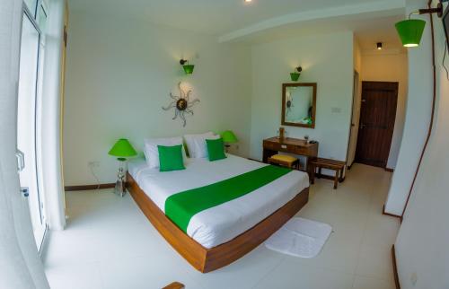 a bedroom with a large bed with green pillows at Chaminrich Homestay in Kandy