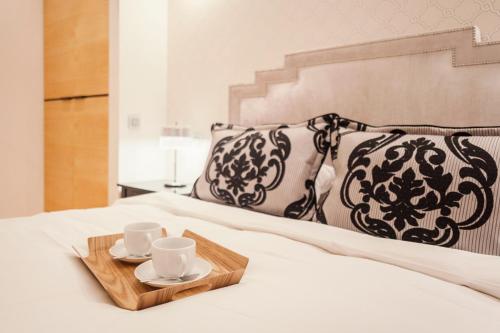 een dienblad met twee kopjes en schotels op een bed bij Świętojańska Old Town Deluxe Apartament by BookingHost in Warschau