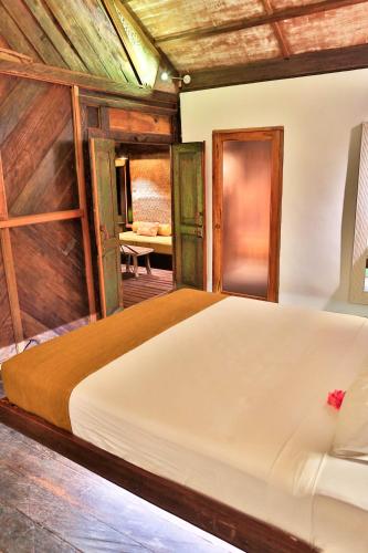 a bedroom with a large bed with wooden walls at Apalagi Villas in Gili Air