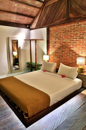 a large bed in a room with a brick wall at Apalagi Villas in Gili Air