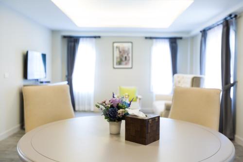 a white table with a vase of flowers on it at Merchant House Chiangmai in Chiang Mai