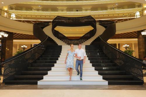 a bride and groom walking down the stairs of a hotel at Sueno Hotels Deluxe Belek in Belek