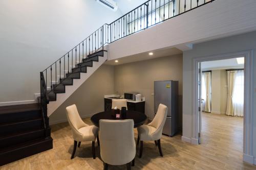 a dining room with a table and chairs and a staircase at Merchant House Chiangmai in Chiang Mai