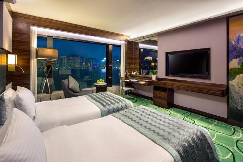 a hotel room with two beds and a television at New World Millennium Hong Kong Hotel in Hong Kong