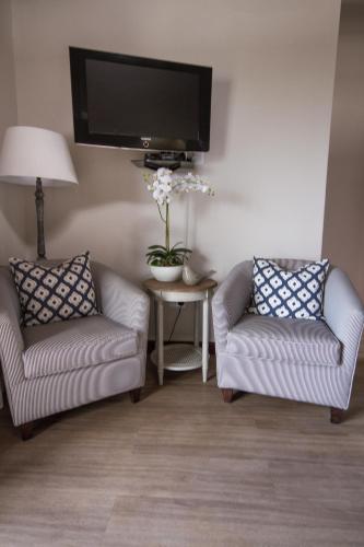a living room with two chairs and a flat screen tv at Little Rock Guesthouse in Jongensfontein