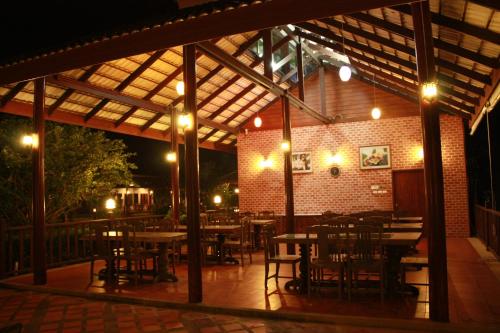 an outdoor patio with tables and chairs at night at Waterside Resort in Pran Buri