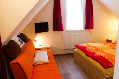 NeuhausにあるFerienwohnungen Dierhagen MOST 892のベッドルーム(オレンジ色のソファ、ベッド付)