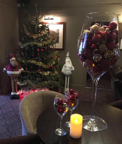 a table with two wine glasses and a christmas tree at Chieftain Hotel in Inverness