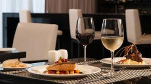 a table with two glasses of white wine and food at Seda Centrio Newly Renovated in Cagayan de Oro