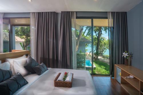 a bedroom with a large bed and a large window at The Bay Samui in Choeng Mon Beach