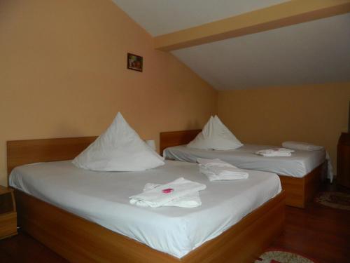 two beds in a room with white towels on them at Complex Turistic Paralela'45 in Băicoi