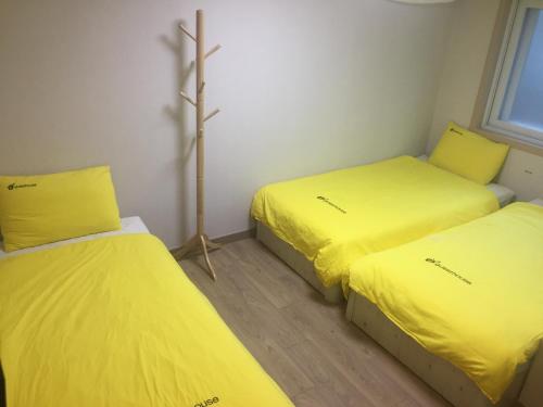 duas camas num quarto com lençóis amarelos em 24 Guesthouse KyungHee University em Seul