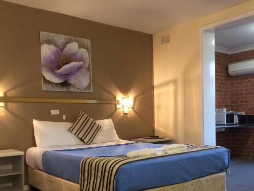 una habitación de hotel con una cama y una pintura floral en la pared en Riverview Motor Inn, en Taree