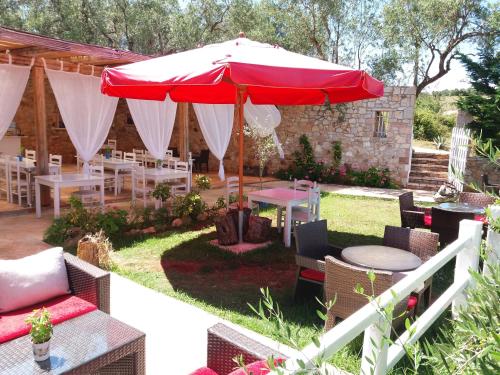 un patio con sombrilla roja, mesas y sillas en Rida Village Ksamil Island, en Ksamil