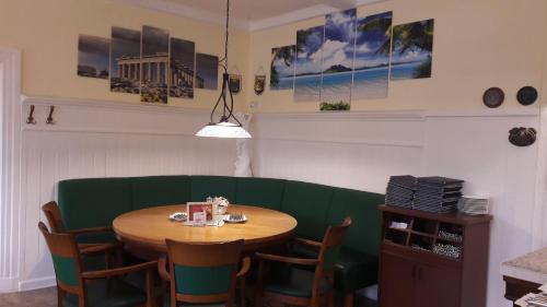 a dining room with a table and a green couch at Hotel Restaurant Hellas in Gelting