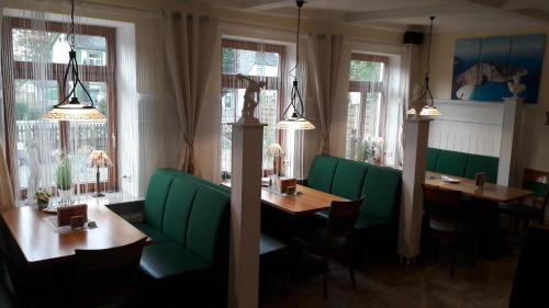 a restaurant with green booths and tables and windows at Hotel Restaurant Hellas in Gelting