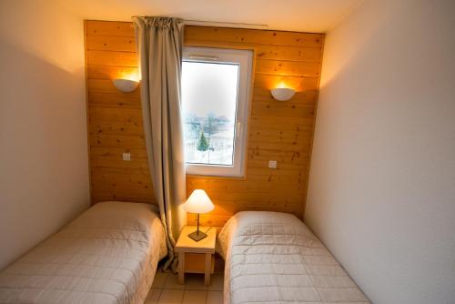dwa łóżka w pokoju z oknem w obiekcie Terres de France - Résidence les Silènes w mieście Allevard