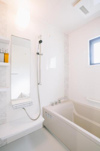 a white bathroom with a tub and a mirror at United Resort Sarabeth in Onna