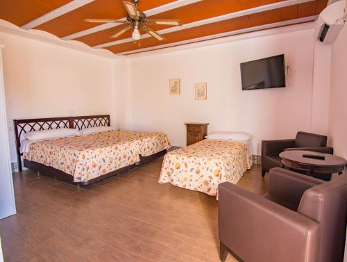 a room with two beds and a flat screen tv at Hotel Rural El Cortijo in Ronda