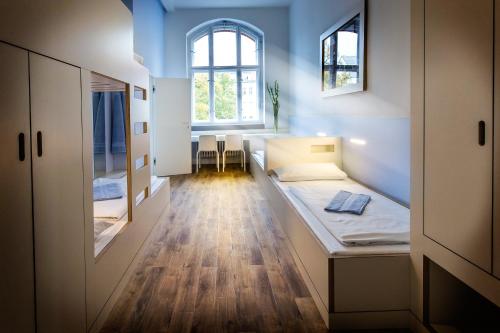 een kleine kamer met een bed en 2 ramen bij Jugendherberge Berlin Ostkreuz in Berlijn