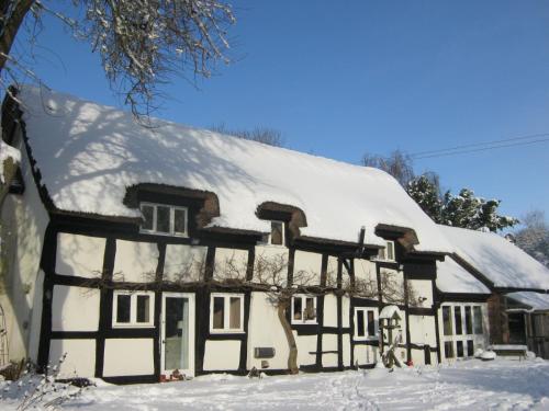 a house covered in snow at THE MOATS - CODDINGTON A small private thatched cottage B&B located in quiet countryside between Ledbury and Malvern - convenient for the Malvern Three Counties Showground and 5 miles from excellent shops restaurants and Ledbury Poetry Festival in Ledbury