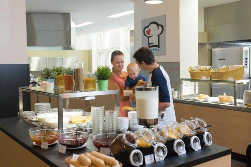 een vrouw en een man die een baby vasthouden in een keuken bij Jugendherberge Berlin Ostkreuz in Berlijn