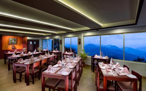 a restaurant with tables and chairs with mountains in the background at Munnar Tea Hills Resort - MTHR in Munnar