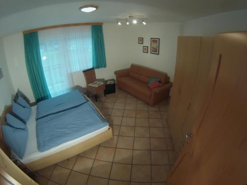ein kleines Schlafzimmer mit einem Bett und einem Sofa in der Unterkunft Appartement Millennium in Bad Gastein