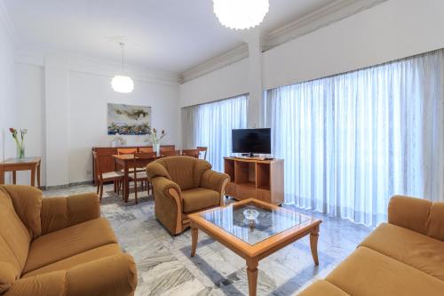 a living room with chairs and a table and a television at Les Palmiers House in Larnaka