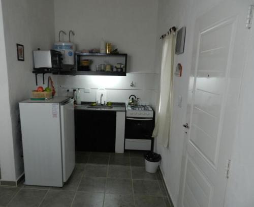una pequeña cocina con fregadero y nevera. en Ruka Inka en Villa Yacanto