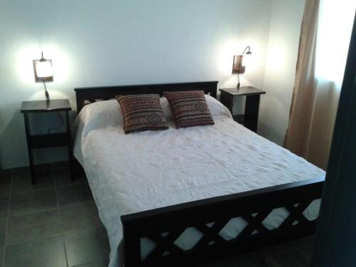 1 dormitorio con 1 cama con 2 lámparas en 2 mesas en Ruka Inka en Villa Yacanto