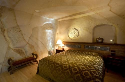 a bedroom with a bed and a stone wall at Fresco Cave Suites Cappadocia in Urgup