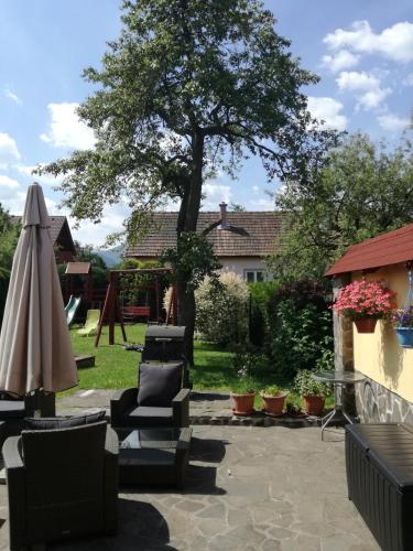 a patio with chairs and an umbrella and a tree at Penzion Fortuna in Liptovský Mikuláš