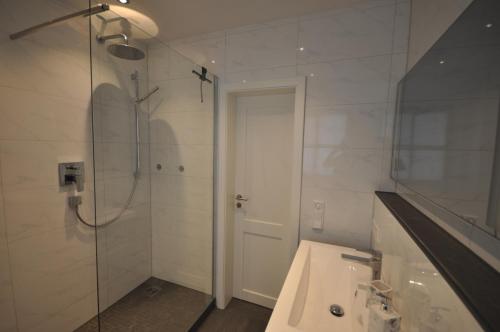 een witte badkamer met een douche en een wastafel bij Apartment am Mohrenplatz in Garmisch-Partenkirchen