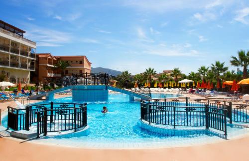 a pool at a resort with a person in the water at Alexander The Great Hotel in Laganas