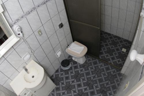 La petite salle de bains est pourvue de toilettes et d'un lavabo. dans l'établissement Hotel Turella, à União da Vitória