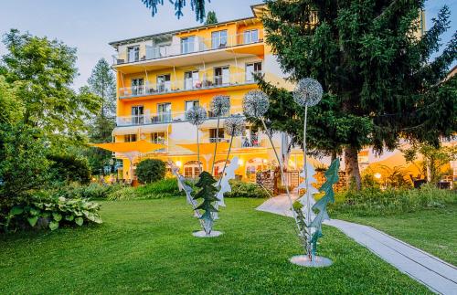 two metal sculptures in the grass in front of a building at Das Moser - Hotel Garni am See (Adults Only) in Egg am Faaker See