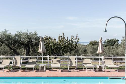 a group of chairs and umbrellas next to a pool at Agriturismo Podere L'Agave in San Vincenzo
